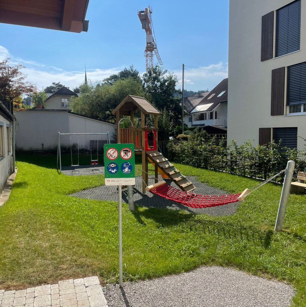 Spielplatz der Spielgruppe Sonnenblume mit Rutsche, Schaukel, Kletterturm und Hängematte im Garten
